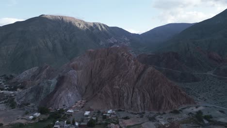 Aerial-Drone-Above-Purmamarca-Town,-Jujuy-Argentina,-Hills-of-Seven-Colors,-Scenic-Mountains,-Sky-and-Andean-Cordillera,-Quebrada-de-Humahuaca,-Travel-and-Tourism-Destination