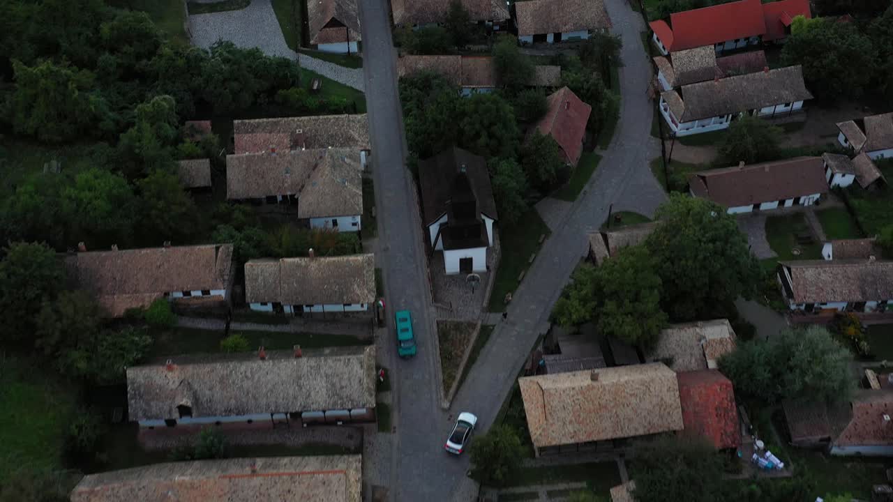 Drone flies over the historical streets of Holloko,Hungary in sunset. Drone looks down and moves forward