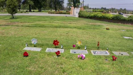 Aerial-close-up-panning-shot-of-headstones-with-floral-decorations-at-a-mortuary-in-California