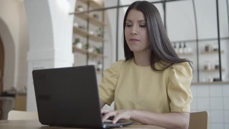 una joven alegre y hermosa que usa una laptop en un espacio de trabajo conjunto