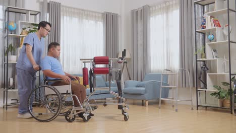 vista lateral completa del cuerpo de un enfermero masculino asiático ayudando a un paciente en silla de ruedas usando un andador para estar de pie durante una terapia física en casa