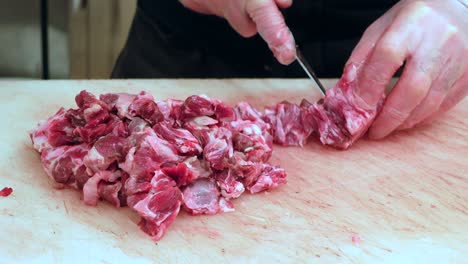 butcher cutting raw meat on a wooden board