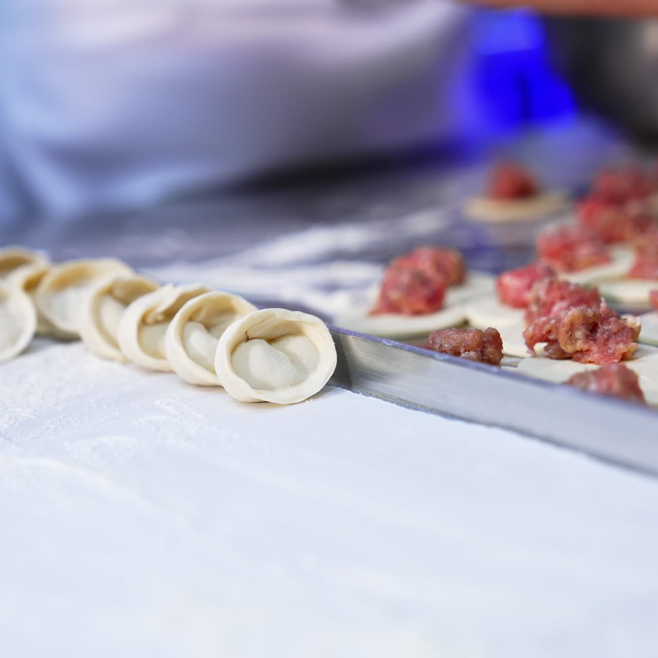 Meat dumplings manufacturing at modern food factory. Workers lay the ready-made ravioli on a tray. Close up