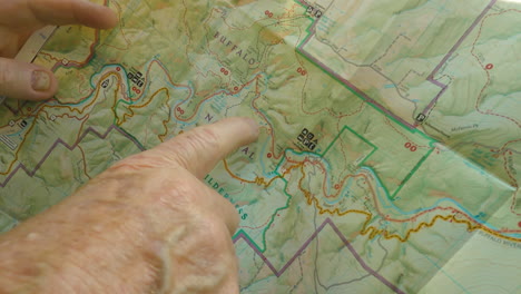 hand showing hiking route on paper map