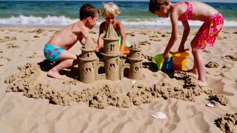 children building a sandcastle on the beach