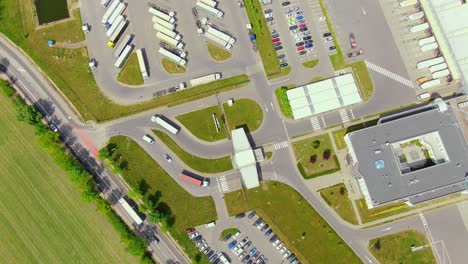 semi truck with cargo trailer is travelling on a parking lot along a warehouse of a logistics park