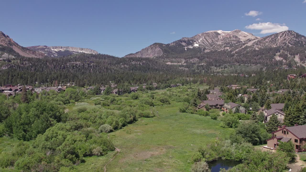4k 드론 푸티지 카메라는 여름에 아름다운 매머드 산 아래로 기울어져 무성한 녹색 초원과 캐빈-1을 볼 수 있습니다.