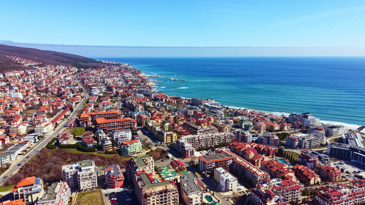 Vista di città costiera con edifici e oceano sotto un cielo azzurro e limpido alla luce del pomeriggio