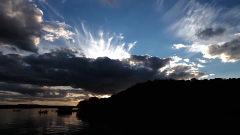 4k-Zeitraffer-Sonnenuntergang-über-See-Und-Kleinem-Berg-Mit-Mehreren-Wolken-Am-Blauen-Himmel