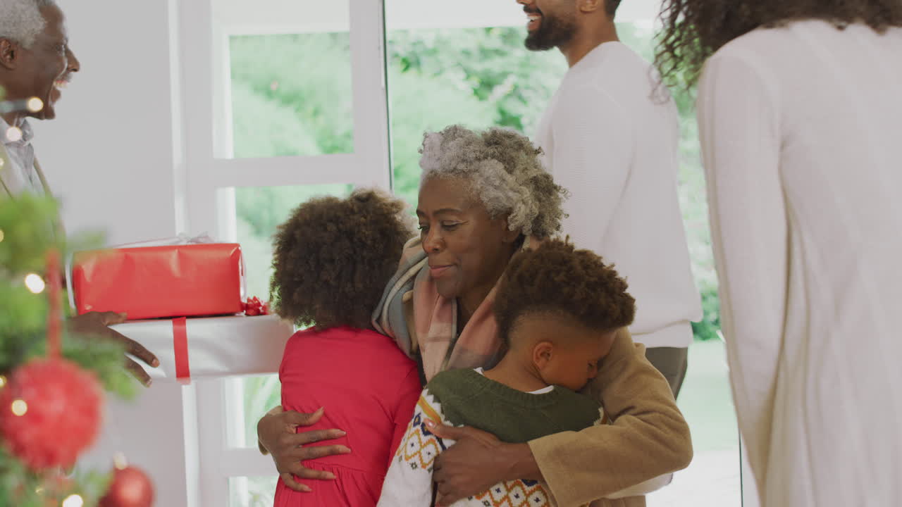 Família cumprimentando os avós enquanto chegam com presentes para celebrar o Natal