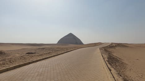 view from the stone road in the desert to the bent pyramid from a great distance