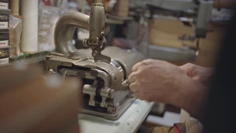 detail of machine and hands of leather craftsman while thinning leather belt