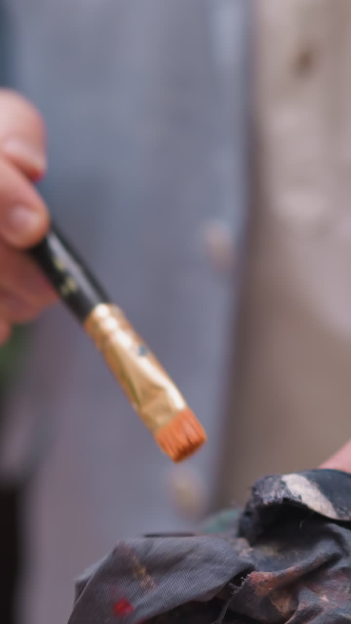 예술가는 질에서 과도한 페인트를 니다. 숙련된 화가는 페인트 도구를 유지하는 데 규율적 인 접근 방식을 보여줍니다. 예술 도구의 품질.