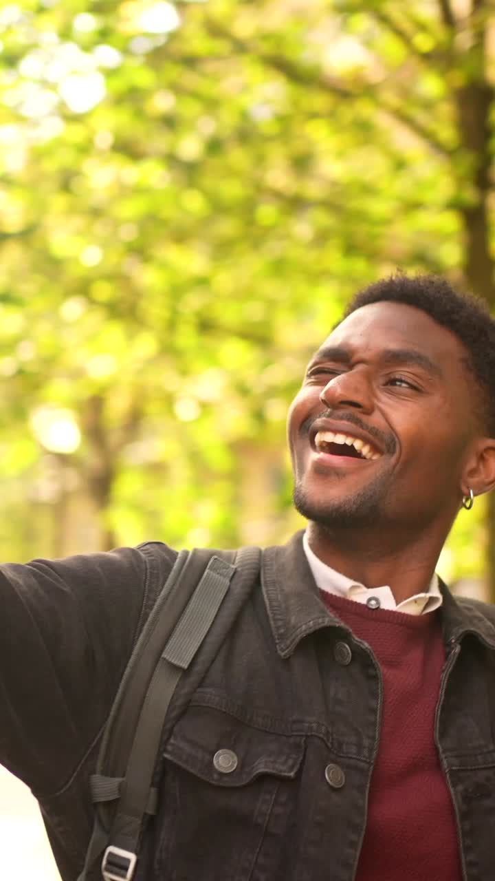A young man with earrings wearing a jacket and backpack outdoors