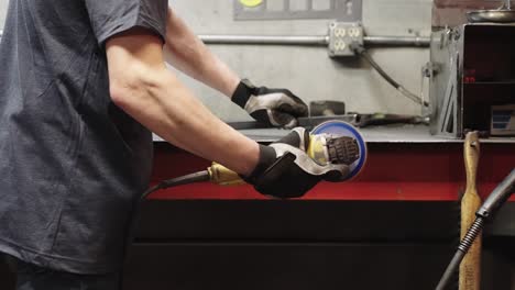 Close-up,-metal-worker-grinding-metal-on-a-work-station-in-metal-workshop,-slow-motion