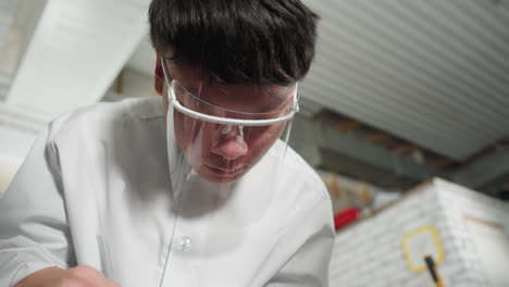 close up of professional in lab coat wearing safety goggles, using vernier caliper to measure engine components in automotive workshop