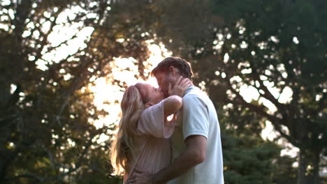 una pareja encantada besándose frente a la puesta de sol.