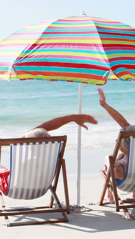 una pareja de ancianos jubilados acostados en una silla de sol mientras dan cinco de alto