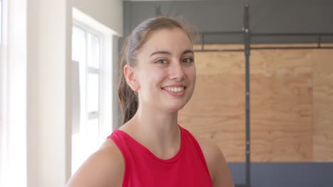 retrato de una feliz mujer caucásica inalterada tomando un descanso del entrenamiento cruzado en el gimnasio, cámara lenta