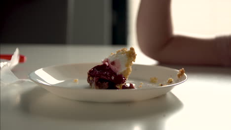 teller mit köstlichem kuchen auf dem tisch, der von einem kleinen jungen im haus gegessen wird