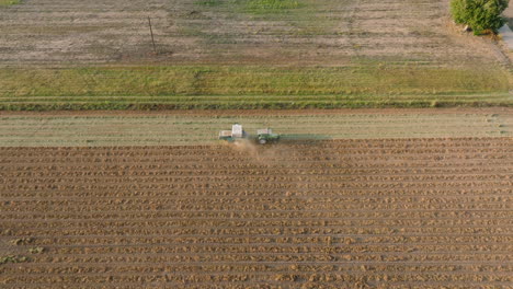 Aéreo:-Seguimiento-Lateral-De-Un-Tractor-Arando-El-Suelo-Durante-La-Puesta-De-Sol