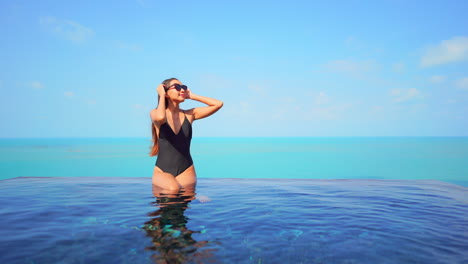 Modern-Woman-at-Sunny-Infinity-Swimming-Pool-Border,-Ocean-Background