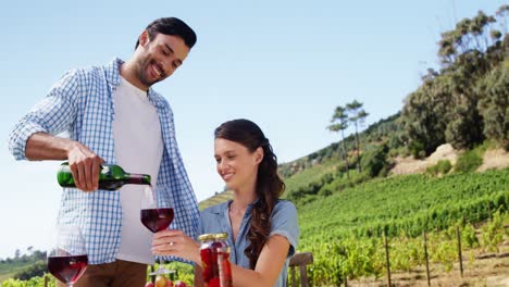 hombre sirviendo vino tinto a una mujer en la granja