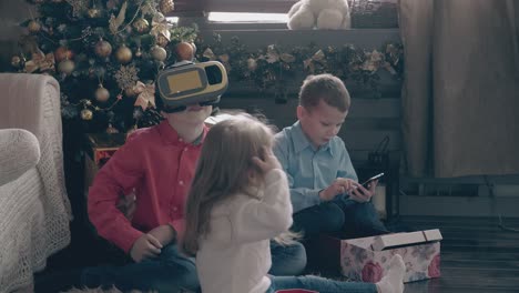 los niños pequeños juegan con aparatos modernos y la niña abre el regalo.