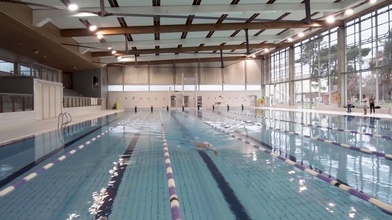 AERIAL SHOT OF A MAN SWIMMING IN A POOL