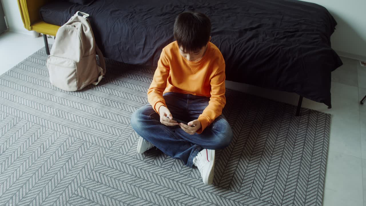 Boy playing smartphone in bedroom