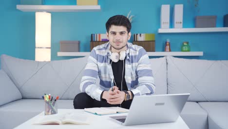 Joven-Estudiando-En-Casa-Mirando-A-La-Cámara.