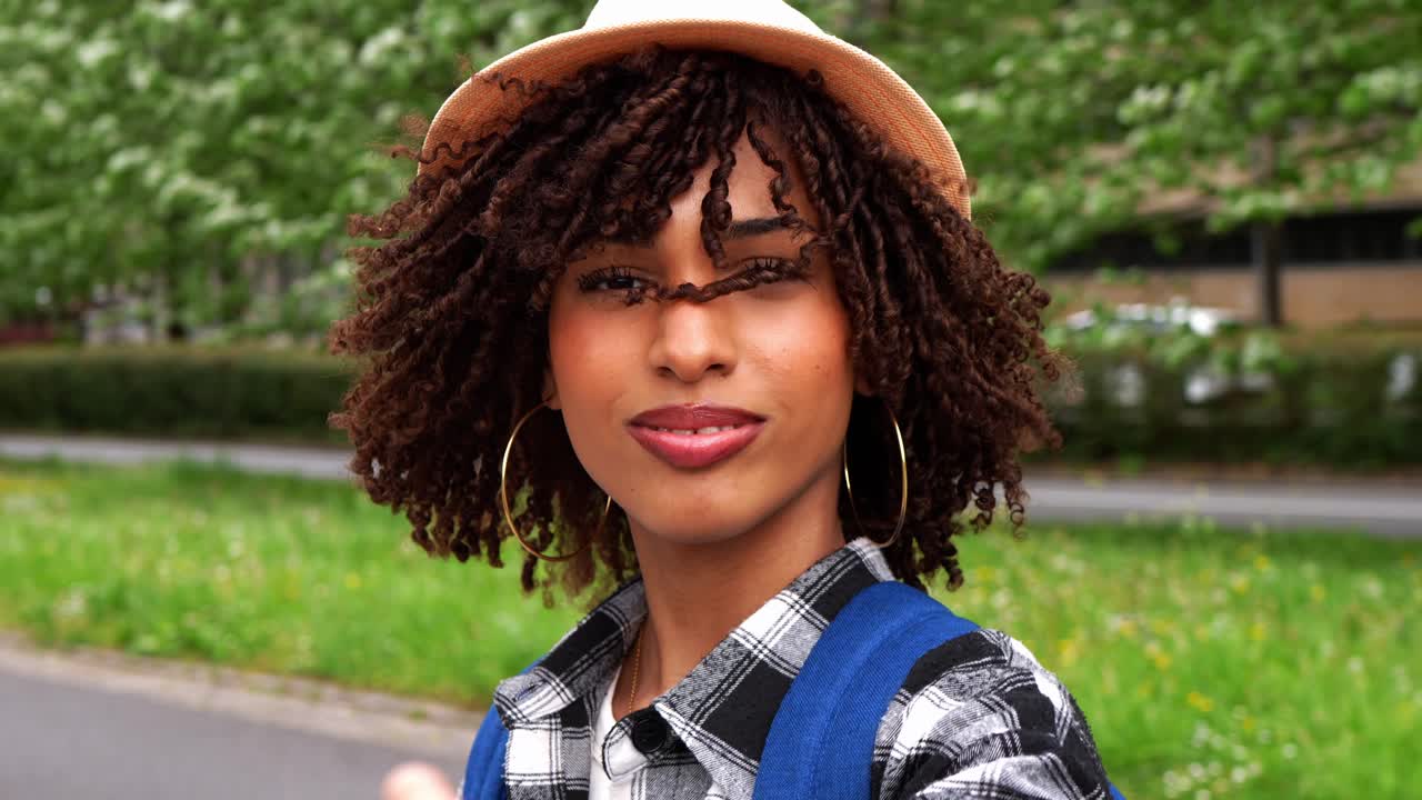 Ritratto di una donna con cappello e capelli ricci all'aperto