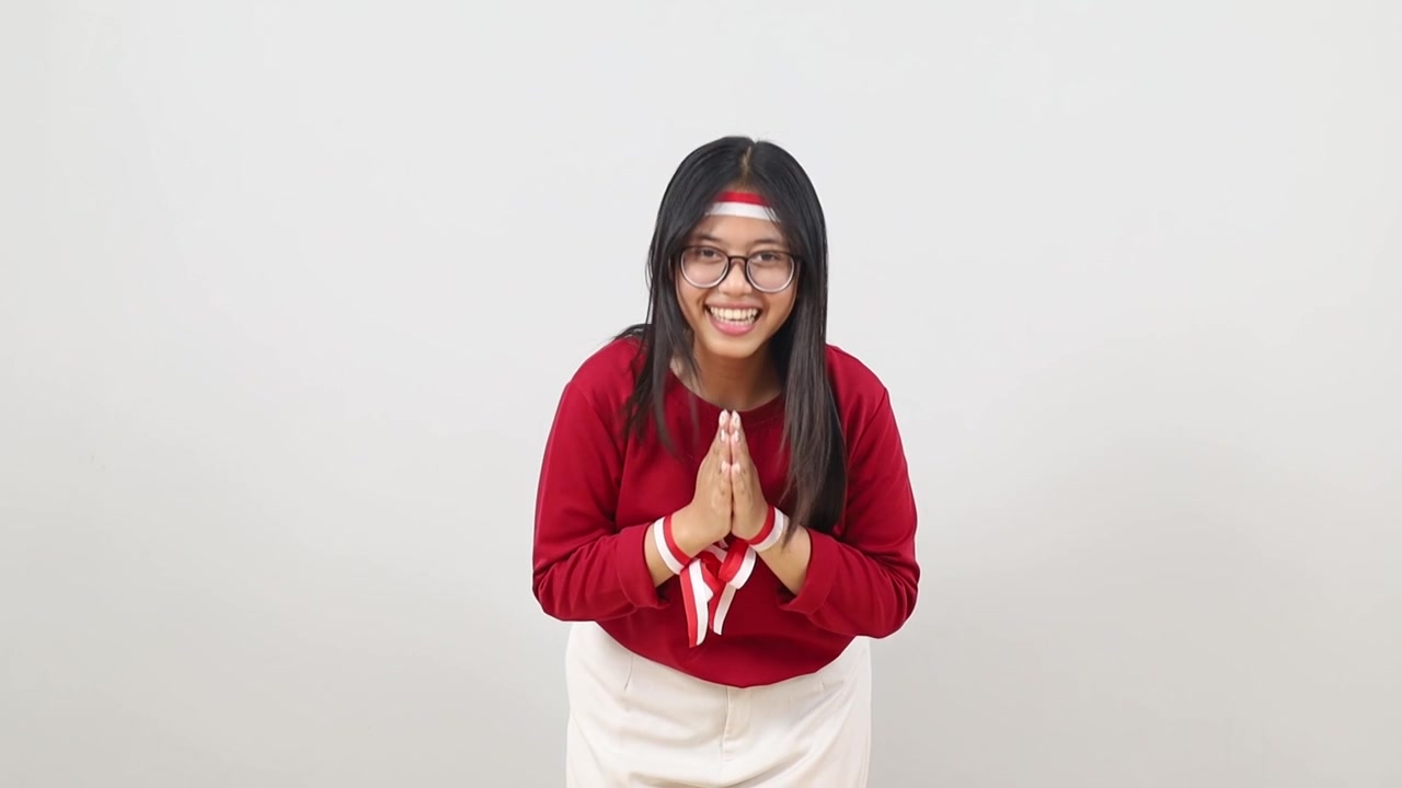 Young Pretty Indonesian woman making Namaste greeting gesture with Indonesia Independence day concept