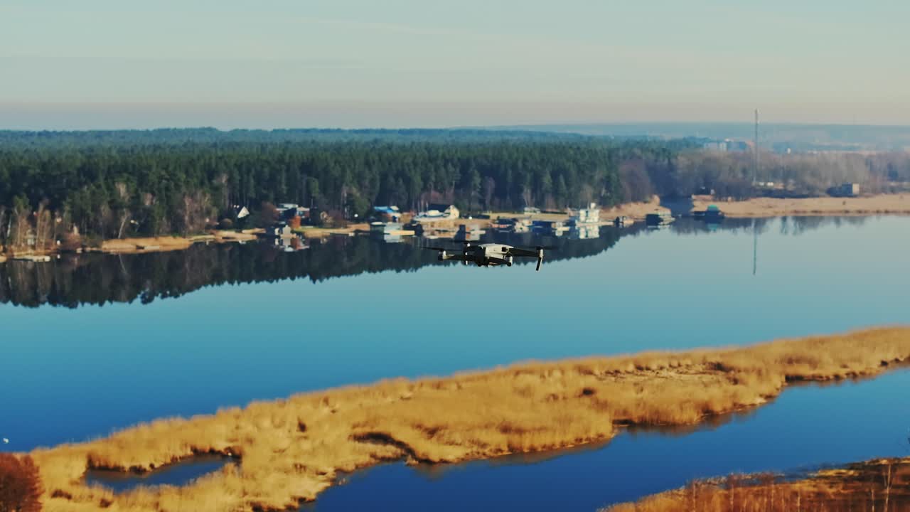 Aerial view of a drone flying above a calm spring river with a mirrored surface