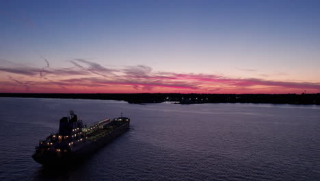 Gravel-Cargo-Ship-With-Lights-Floating-Off-The-Shore-Of-Kingsville-In-Ontario,-Canada-At-Twilight