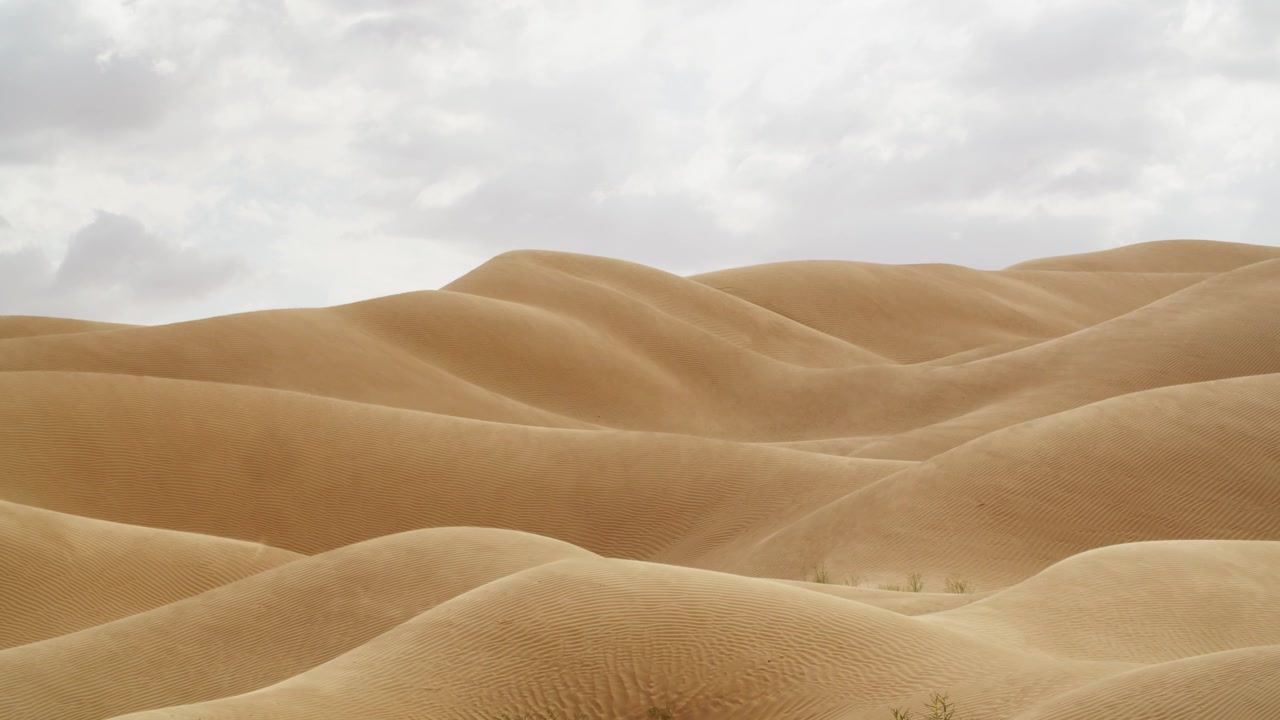 Ripresa aerea con drone sulle infinite onde di sabbia del Grande Erg Orientale in Tunisia, che mostra la sabbia sollevata dal vento che crea una leggera foschia sul Sahara