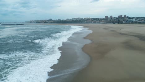 Drone-aerial-view-coast-seascape-beach,-atlantic-ocean-waves-wash-on-shore,-city-town-porto-portugal-background