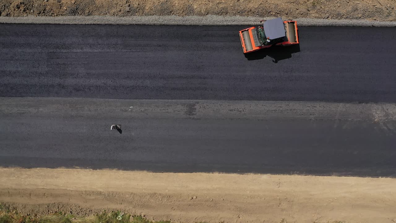 Road roller machine rolls asphalt. Aerial view on the road rollers working on the new road construction site