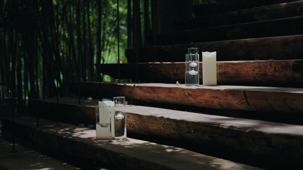 simple candle arrangement along wooden steps in dappled forest lighting