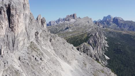 Aerial-panning-shot-of-Sass-de-Stria-Mountain-and-Cinque-Torri-in-Background-during-a-sunny-day