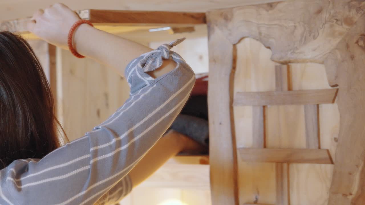 Person arranging clothes in wooden furniture, cozy home setting, focus on organization.