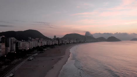 Aerial-pan-of-the-sun-rising-next-to-the-Sugarloaf-mountain-revealing-Copacabana-beach-and-neighbourhood