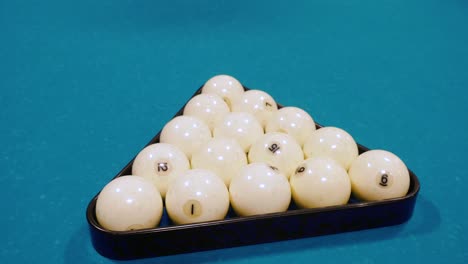 pool balls arranged in a triangle on a teal pool table