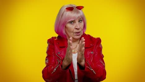 una mujer mayor feliz con cabello rosa le da un pulgar hacia arriba.