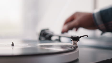 man puts phono stylus on vinyl disk in turntable. male music lover fills day with joy of listening to music on vintage device. old-school collectible vinyl