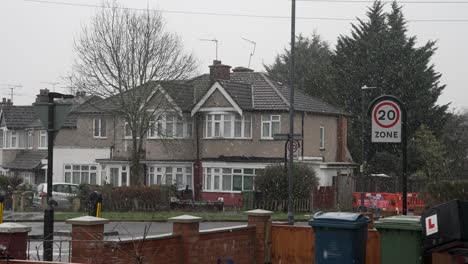 nieve cayendo en una calle residencial en grada en un día nublado