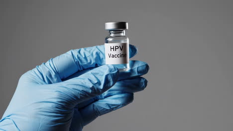 hand in gloves holding hpv vaccine vial