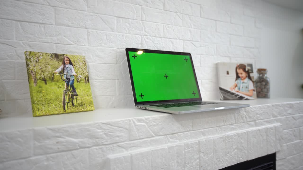 una computadora portátil de pantalla verde sentada en un escritorio de trabajo en casa junto a una lámpara de escritorio.