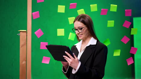 woman sharing ideas in office. a woman in a black suit reads from a tablet in a colorful brainstorming environment filled with sticky notes