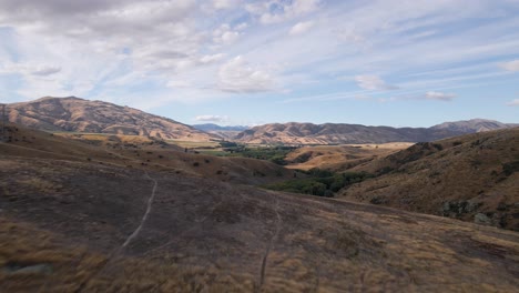 drone flight over ridge revealing truck driving down mountain pass through rugged terrain